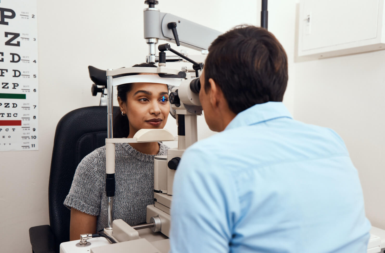 A female patient receiving an eye examination from a male optometrist